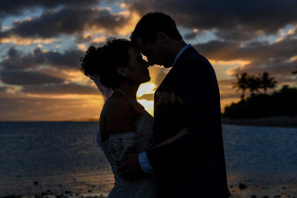 Mid closeup Silhouette shot of bride and groom against fiery sunset in Fiji