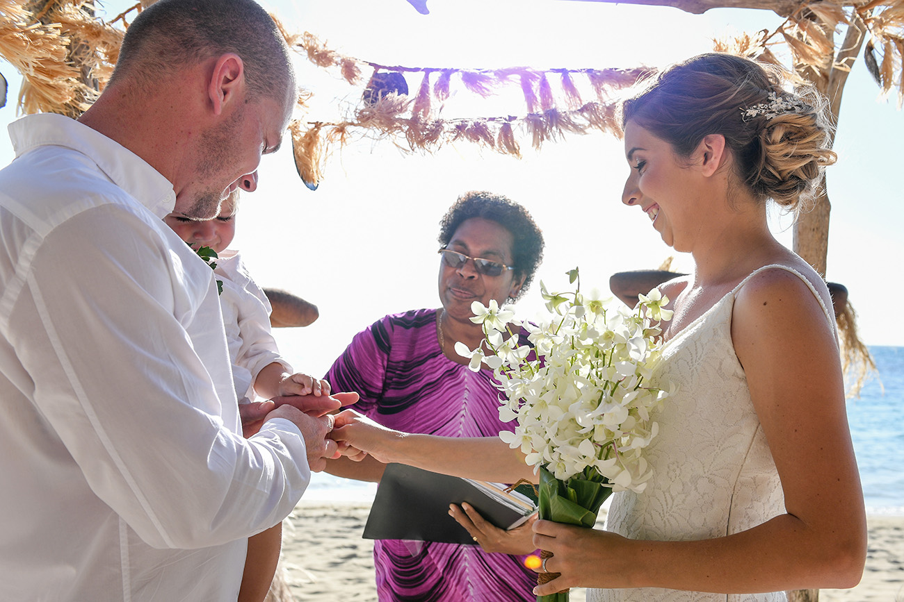 The bride puts the ring on the groom at the Fiji altar.
