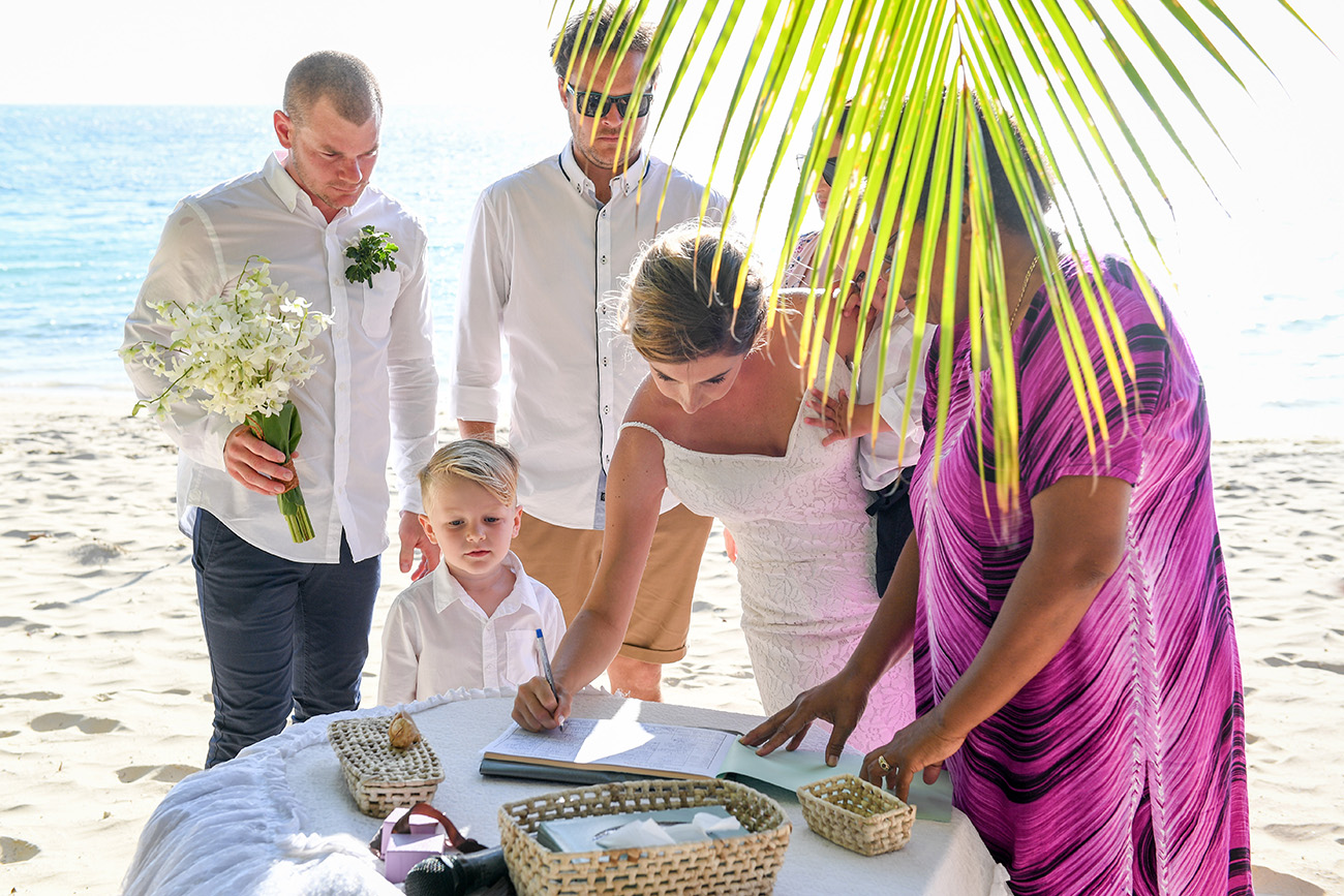 The bride signs the marriage certificate by the beach