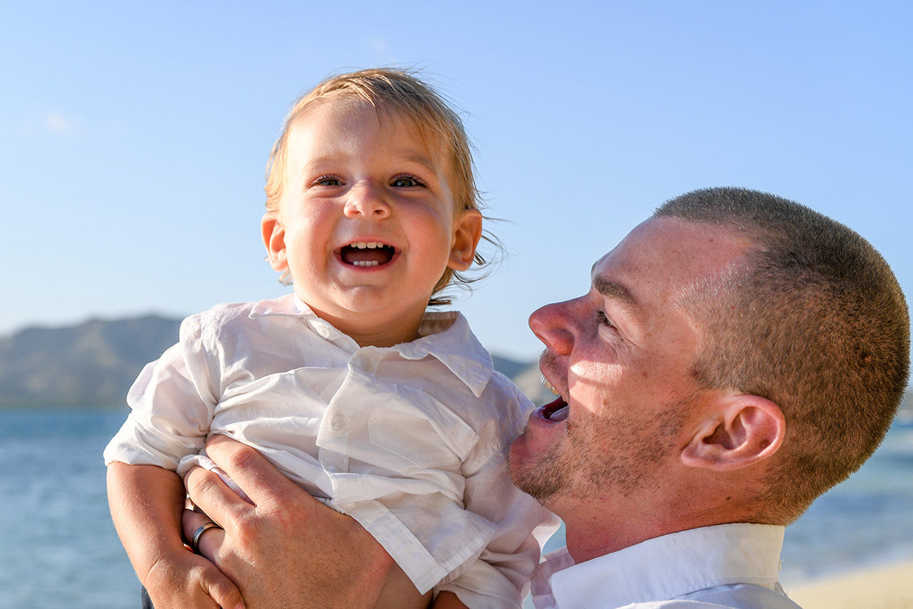 The groom laughs with his son as he lifts him sky high