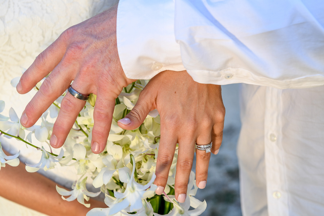 Silver rings on the married couple over the tropical white flower bouquet