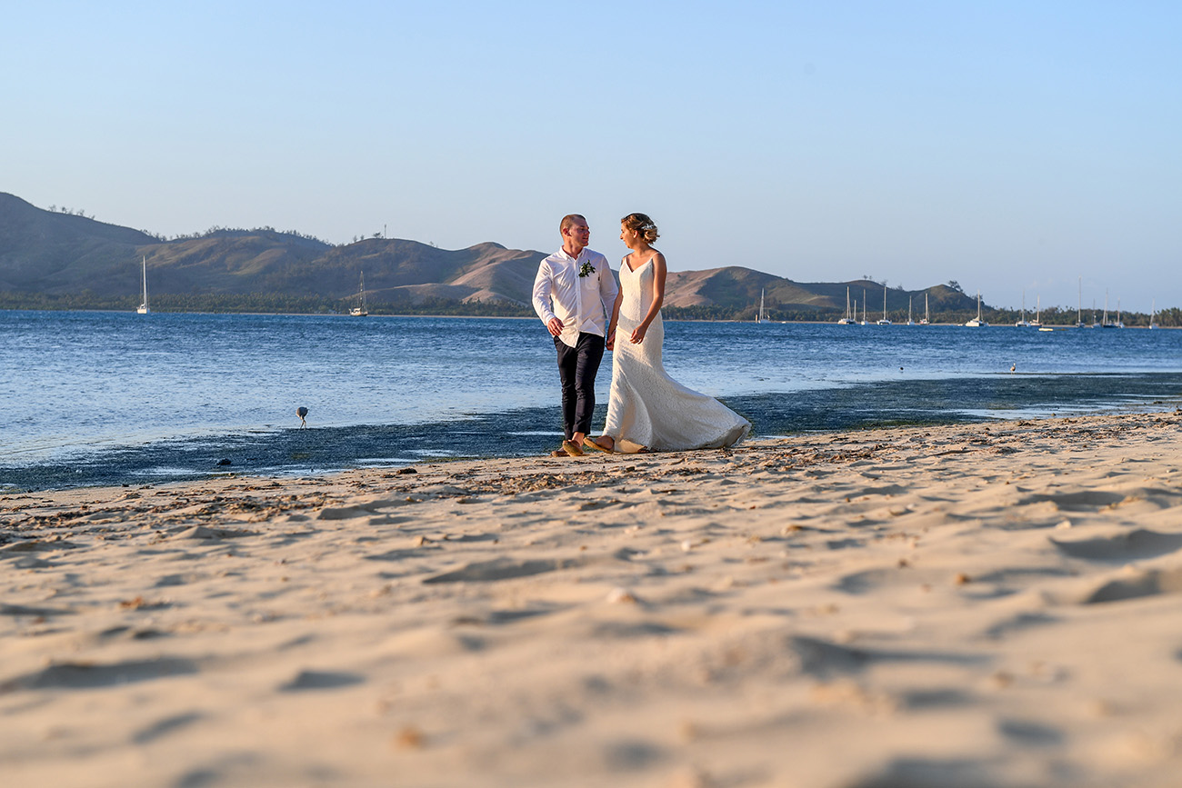 Longshot of bride and groom strolling by the sea