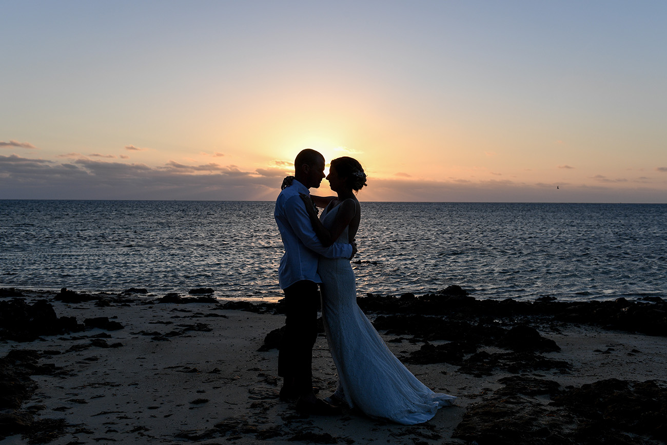 Silhouette and bride and groom kissing against the sunset