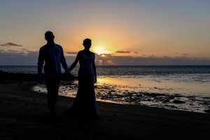 Silhouette of bride and groom against fiery Fiji sunset and the sea