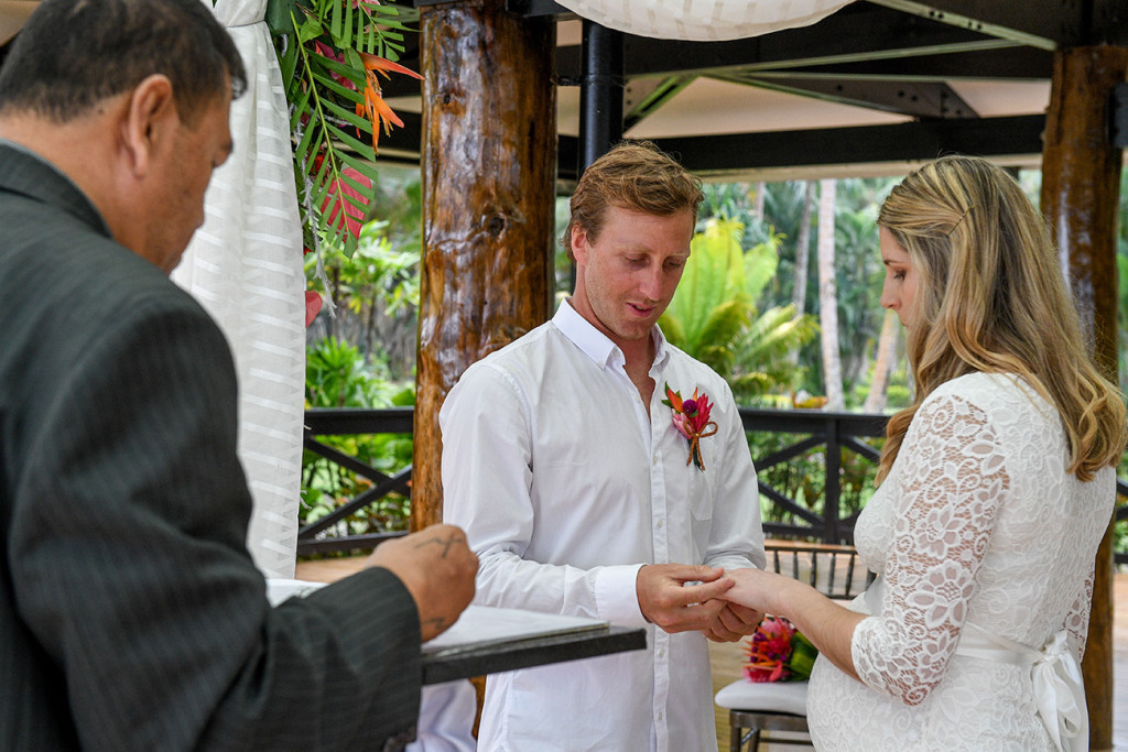 The groom puts the ring on the bride's finger at their elopement in Fiji