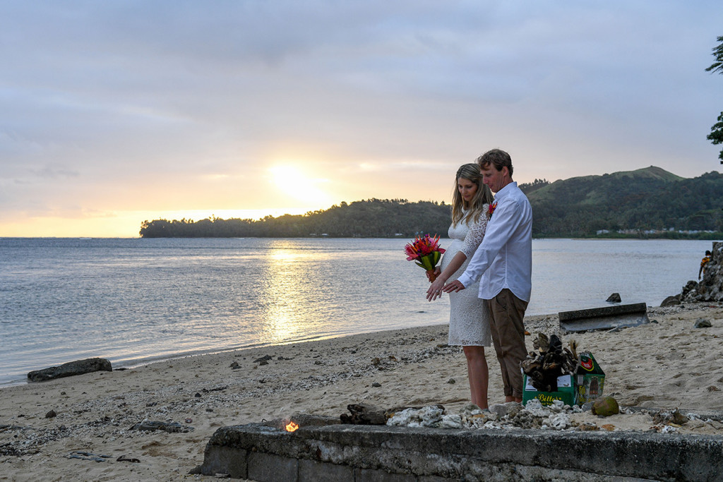 The bride and groom at sunset on the Fiji beach by a bonefire