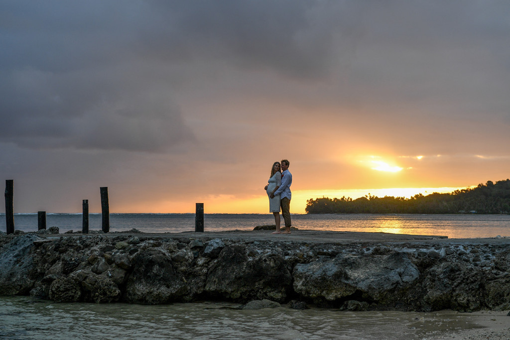The bride and groom at sunset on the Fiji beach looking at the horizon