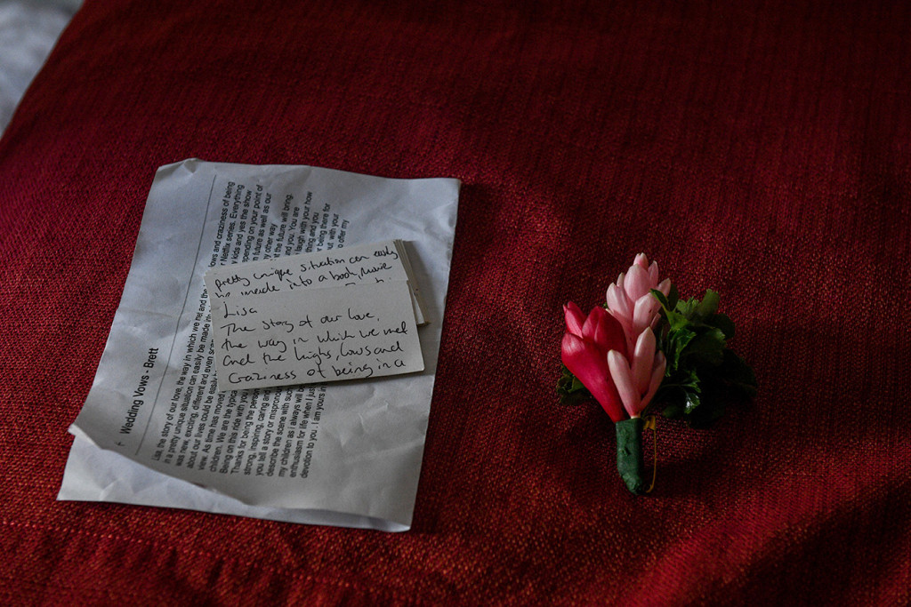 Groom's handwritten vows beside pink flower boutonniere