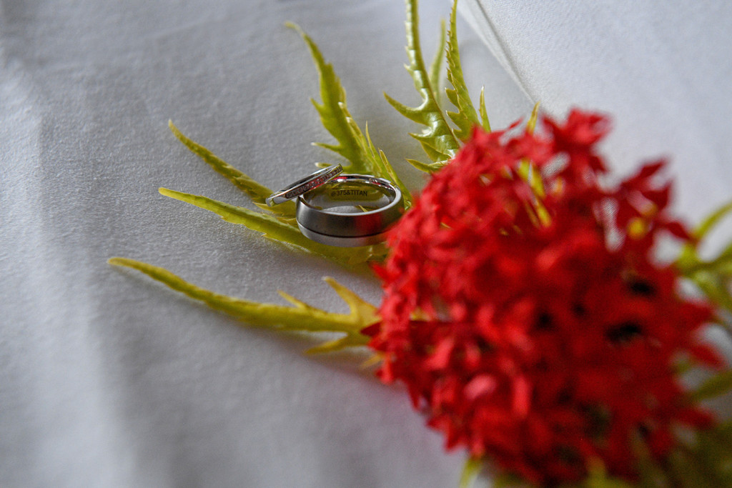 Silver diamond rings by Christopher & Co against crimson tropical flower bouquet