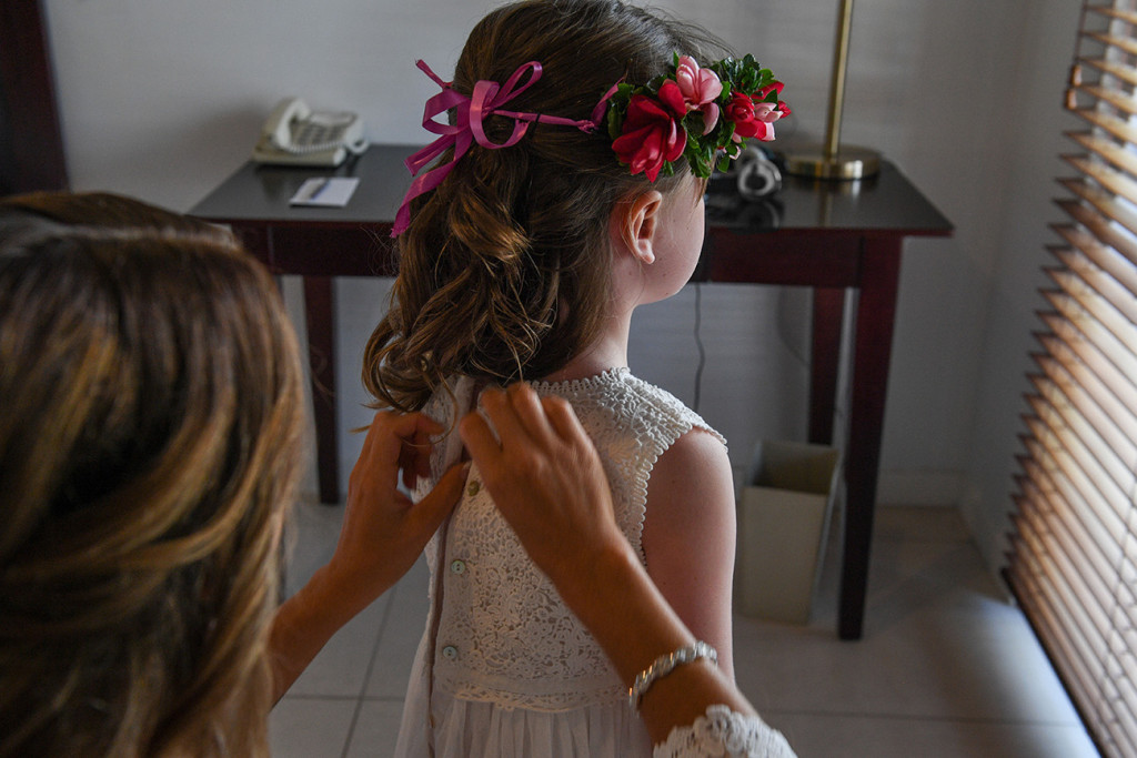 A bridesmaid zips up a flower girl's dress