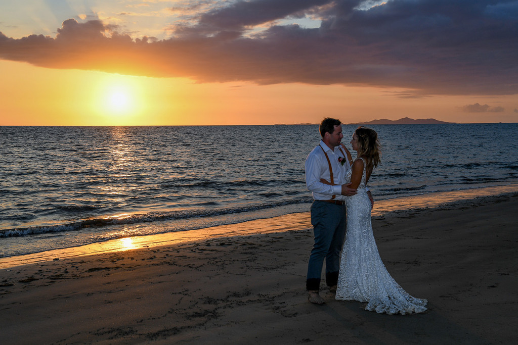 Bride and groom beside the Pacific ocean at sunset