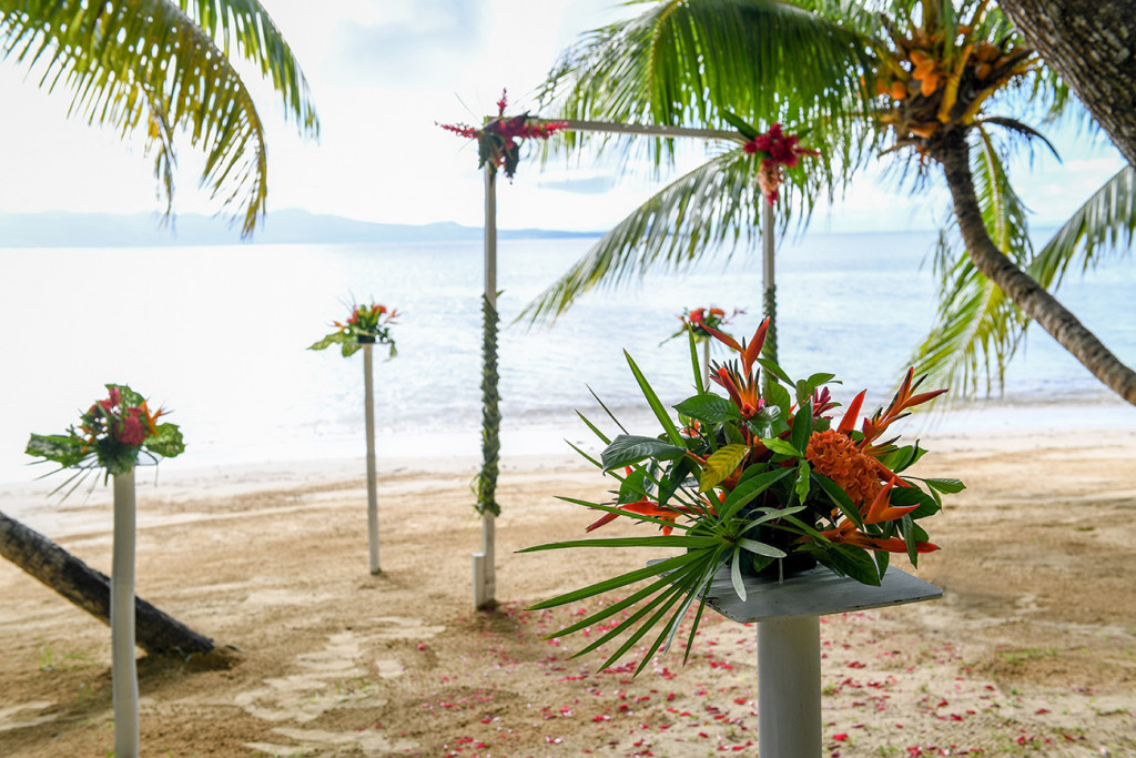 The wedding ceremony set up with an arch and tropcial orange flower at Matangi island resort in Fiji