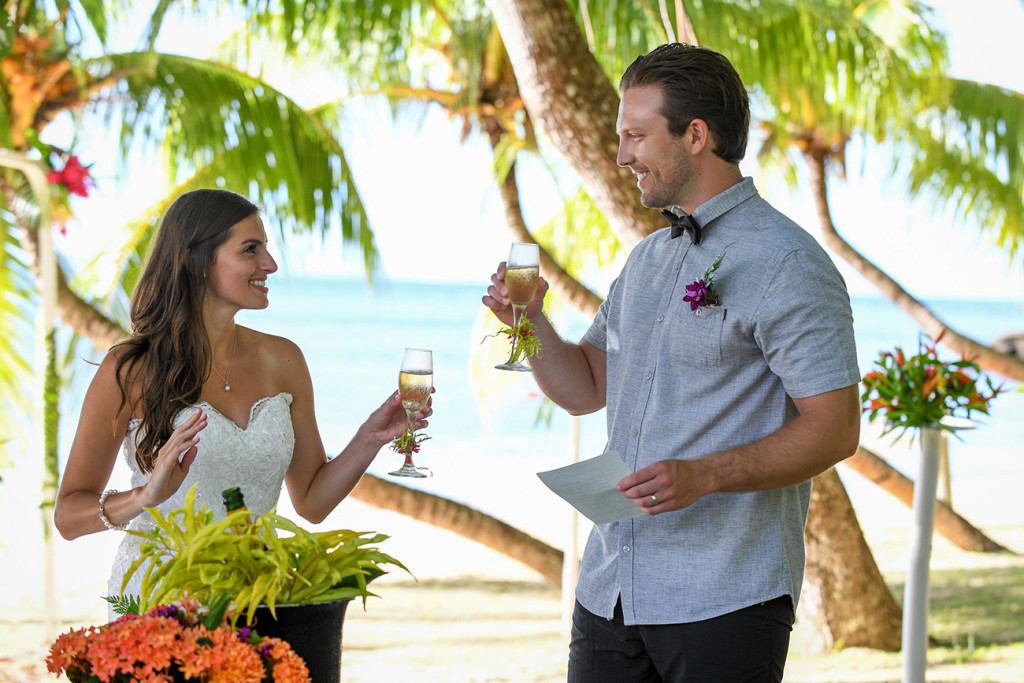 The young married couple cheer with a glass of champagne at Matangi island resort in Fiji