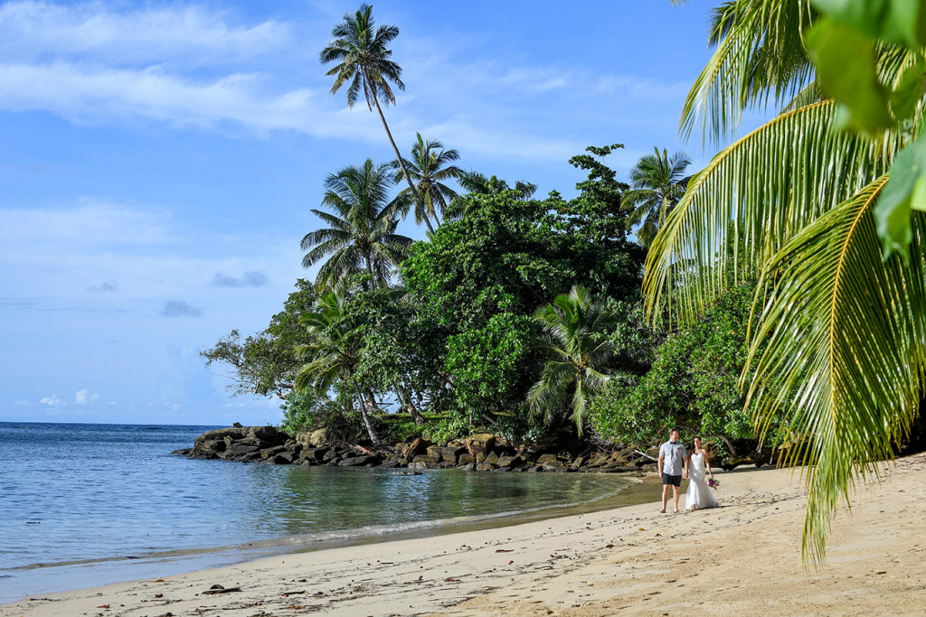 bride and groom walking along the beach, holding hands at Matangi island resort in fiji