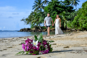 Bride and groom walking with their bouquet in the foreground, Matangi Fiji