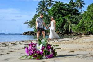 Bride and groom walking with their bouquet in the foreground, Matangi Fiji
