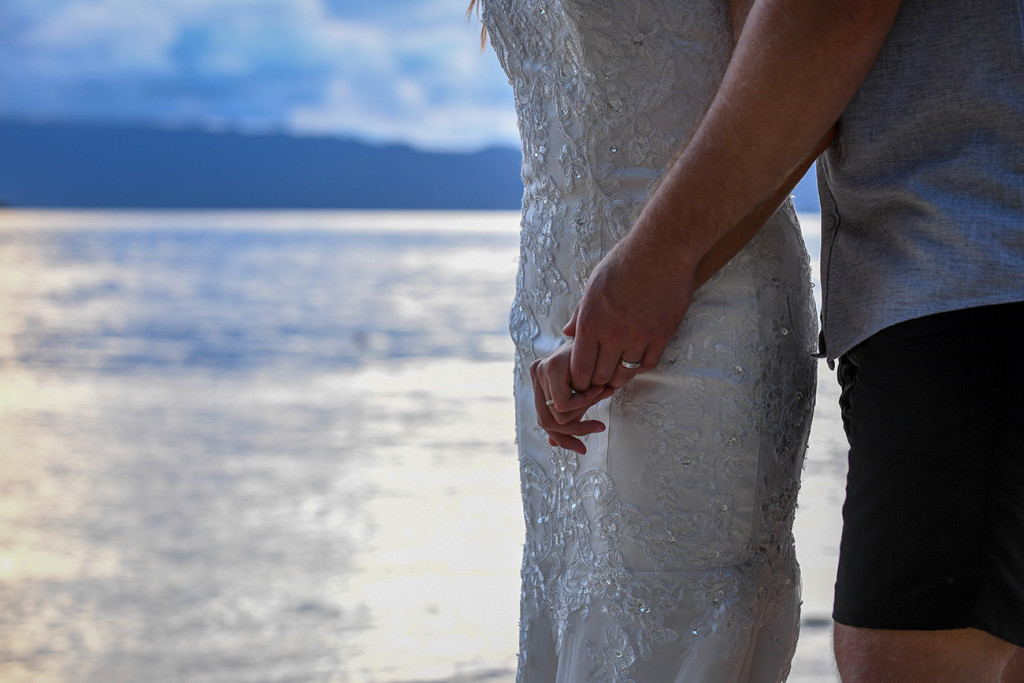 Hands of the bride and groom with their rings and sea in the backgroup, Matangi island resort in Fiji
