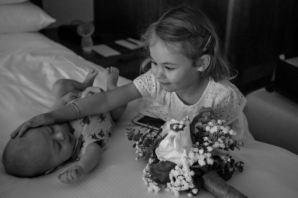 Adorable flower girl playing with her baby brother