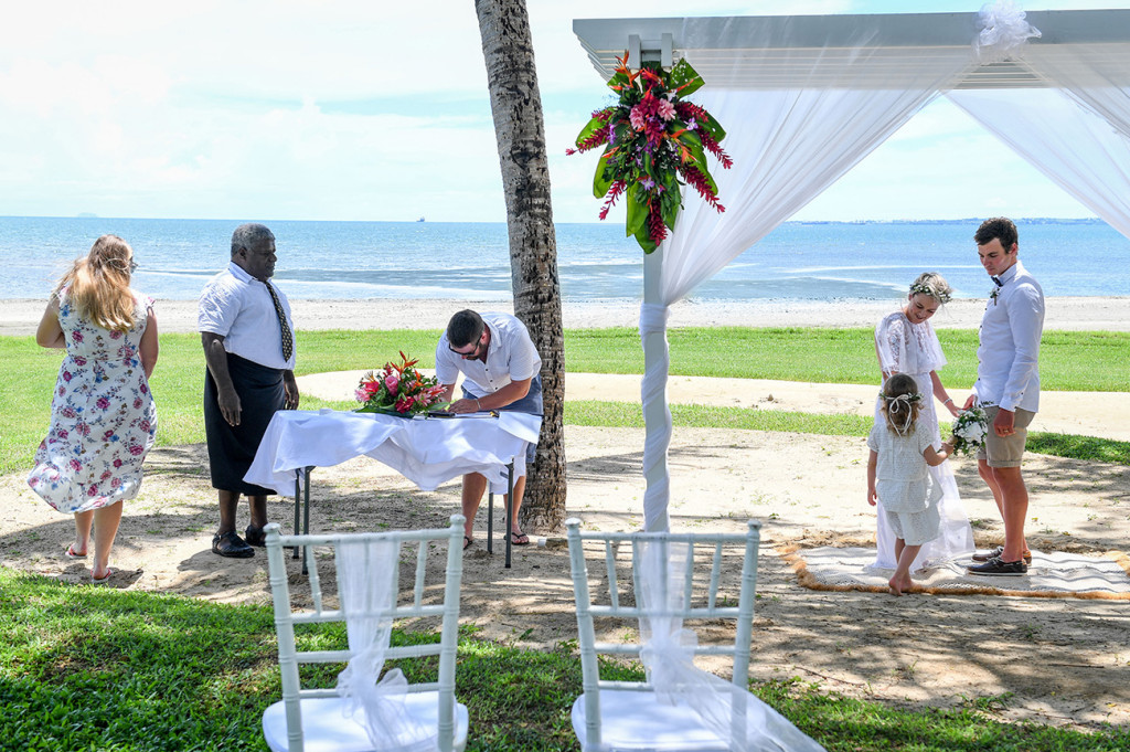 Wedding guest and witness signs marriage certificate at destination beach wedding