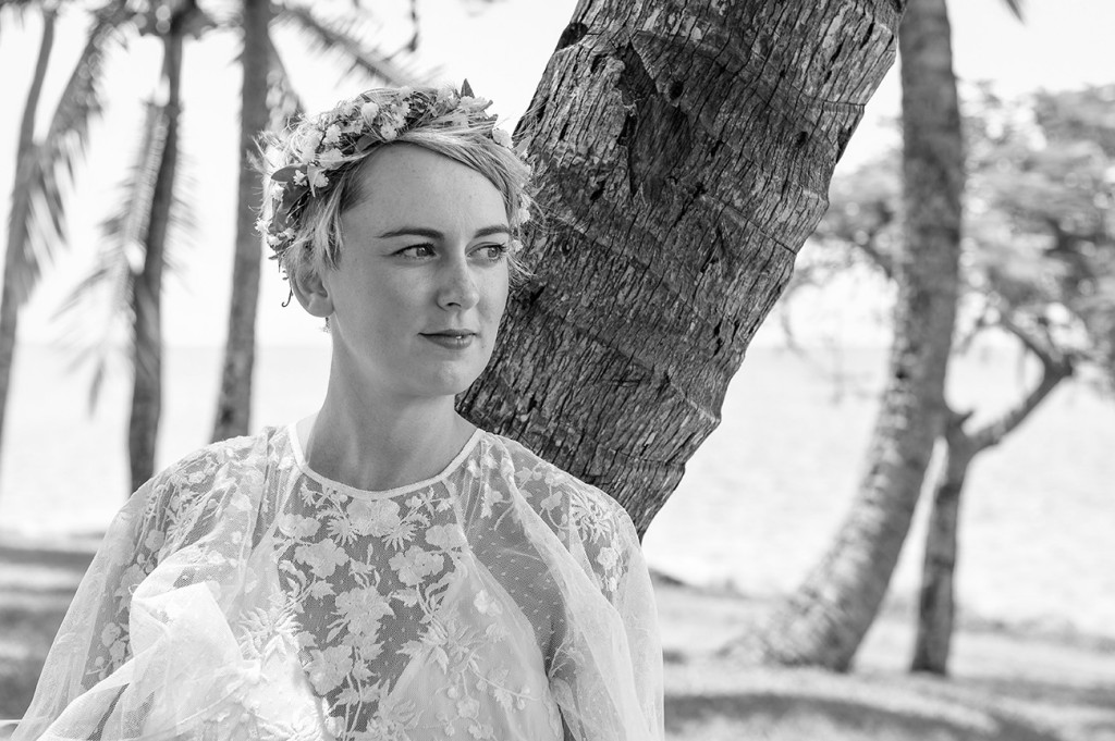Monochrome of the stunning bride leaning against a palm tree