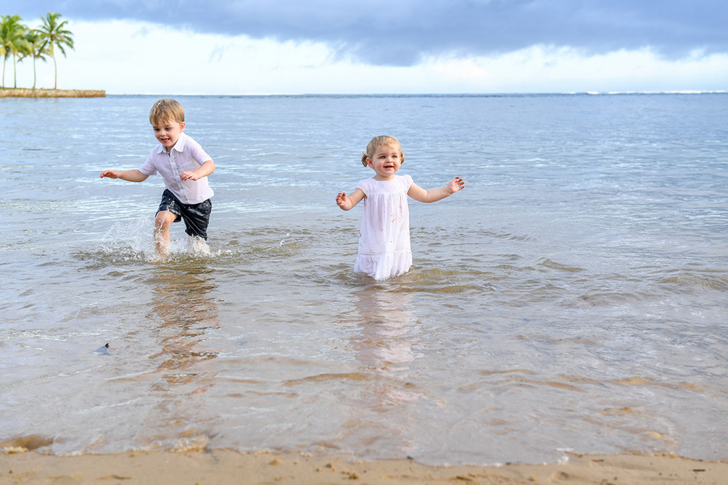 Cute baby brother and sister playing in the Pacific Ocean at Fiji