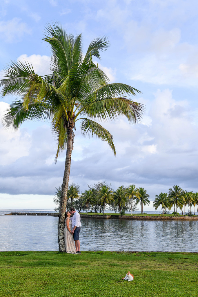 Bride and groom stand against a palm tree at the breathtaking beach of Naviti Fiji