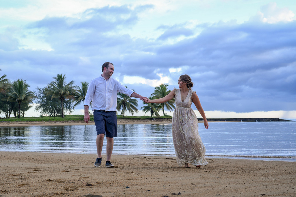 Bride and groom play hand in hand against magnificent susnet at Naviti Fiji