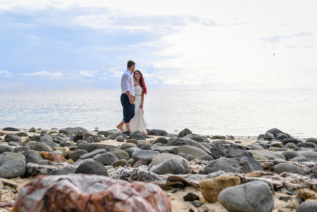 The married couple stand on rocky beach at the Plantation Island Resort