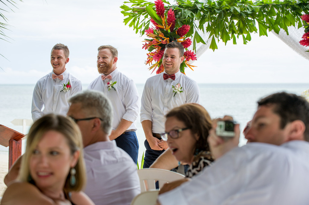 Groom and groomsmen smile as they watch the bride walk down the aisle