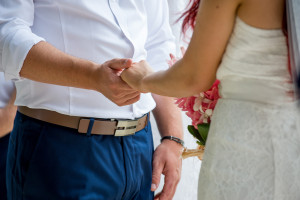 Closeup of the bride and groom holding hands at the ceremony