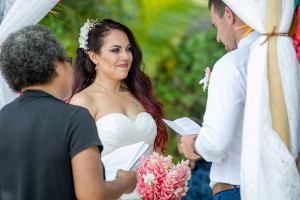 A blushing bride smiles as her groom reads the vows