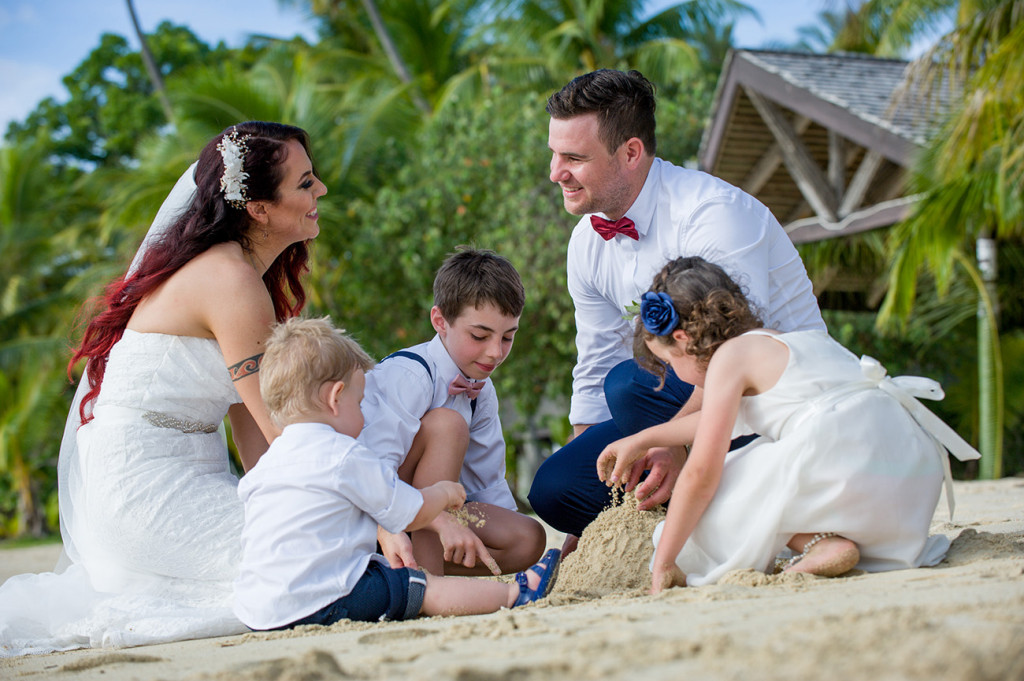 Bride groom and their children build sand castles on the beach