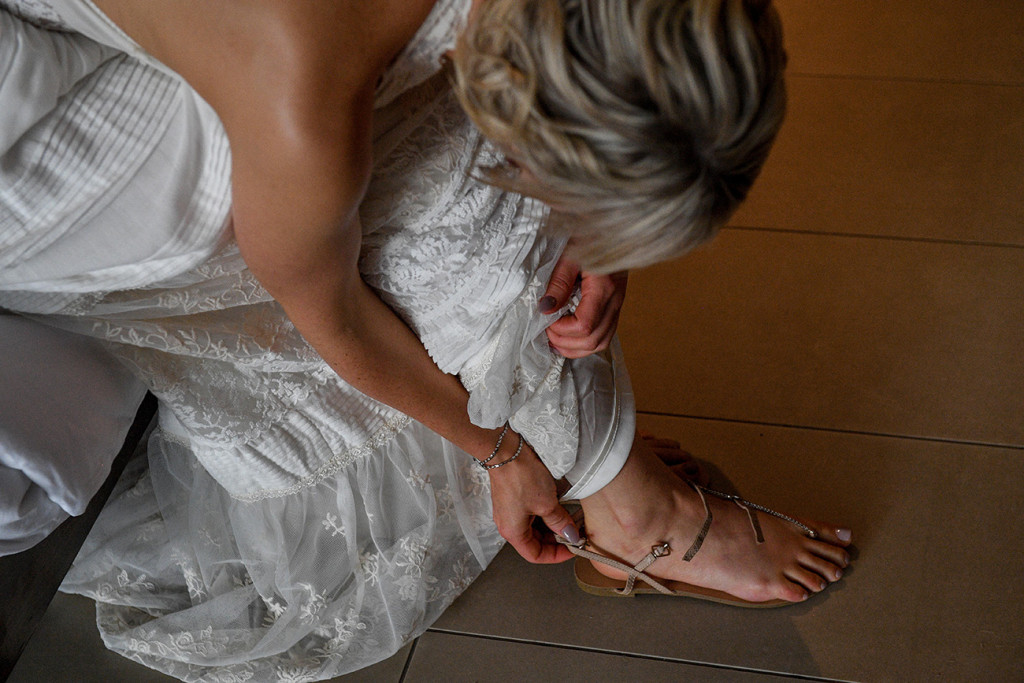 Bride straps her beige wedding sandals by siren shoes