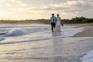 Newly wed bride and groom stroll hand in hand on the Fiji Coral Coast on their elopement