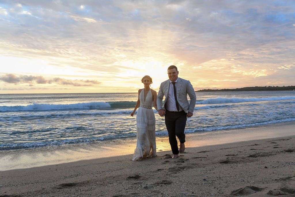Newly eloped man and wife run on the beach against the sunset at Yatule Resort Fiji