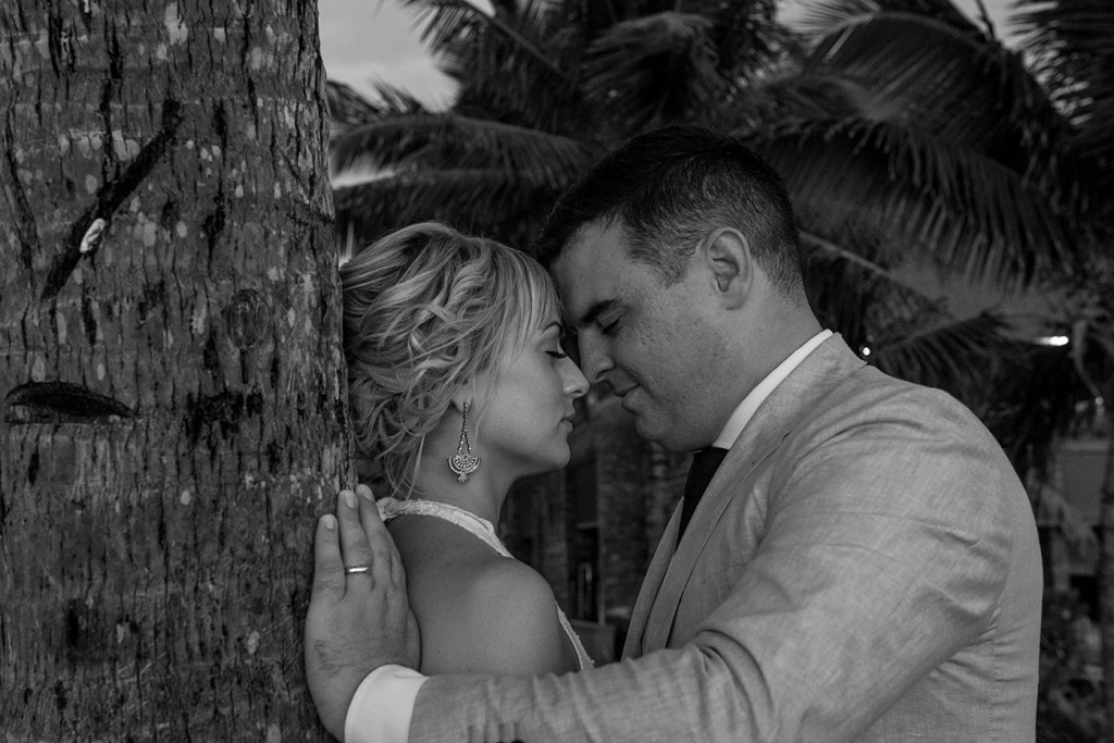 Monochrome candid image of the bride and groom intimate against a palm tree