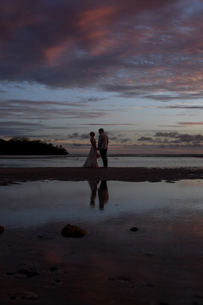 Silhouette of bride and groom in the ocean at dusk