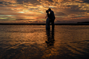Silhouette of bride and groom kissing in the ocean against golden Fiji sunset