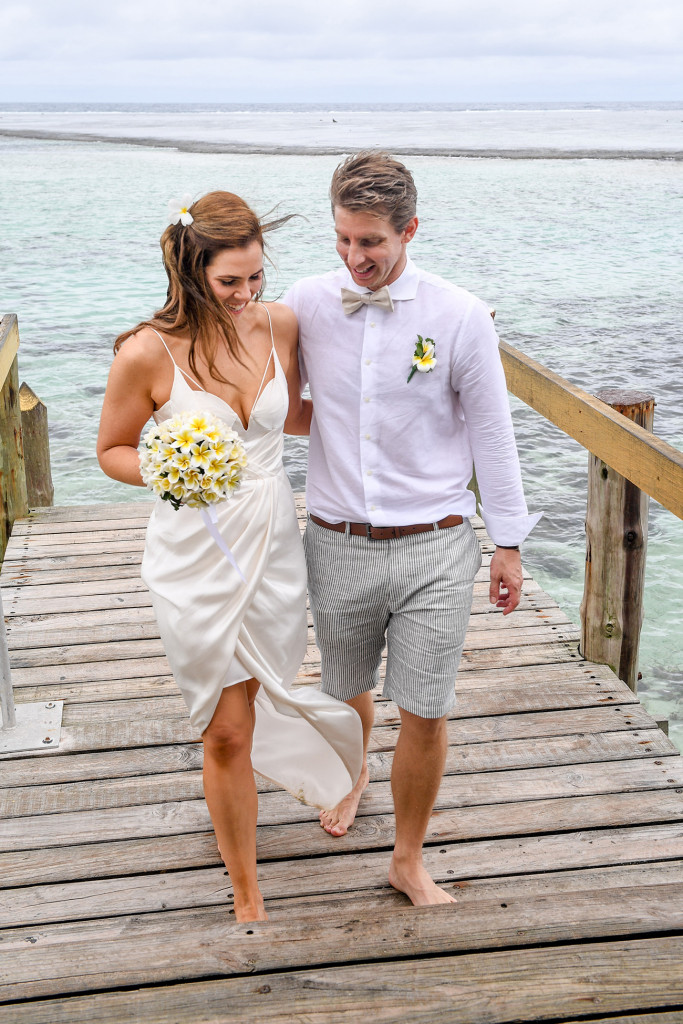 Bride and groom, arm in arm stroll up the docks of Maui bay