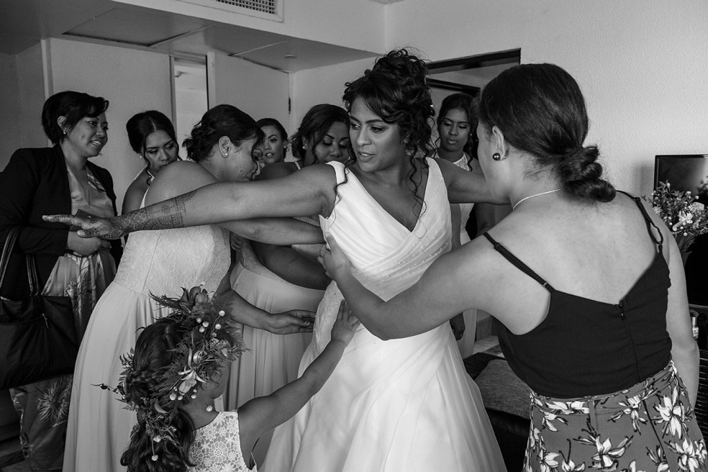 All the bridesmaids help the bride zip her dress