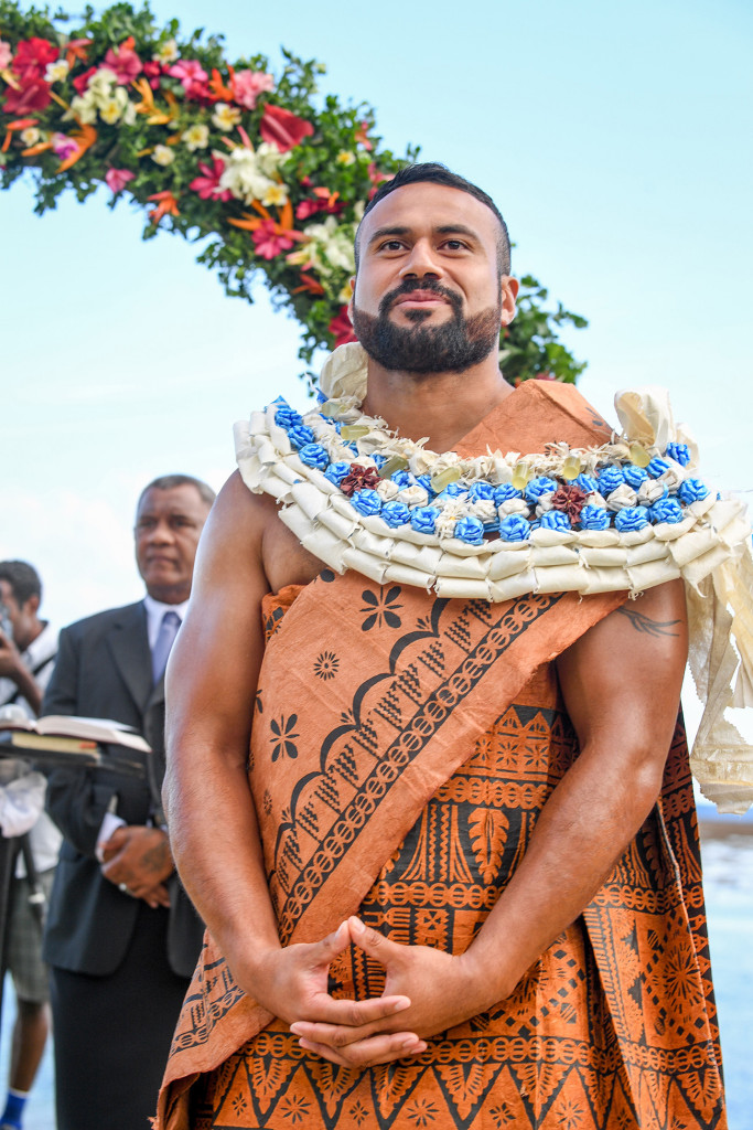 A happy groom in Traditional Samoan Masi and Lei waits at the end of the aisle
