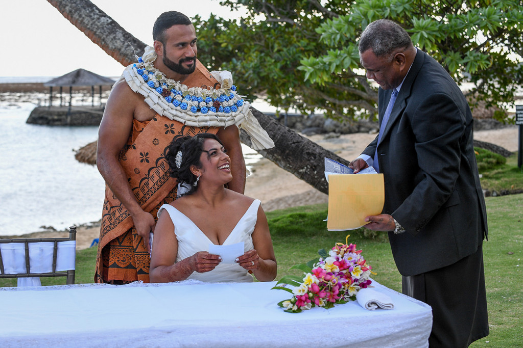 The couple smile at the celebrant who puts the certificate in an envelope