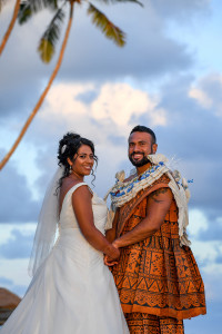 The bride and groom pose for a photo against the baby blue Fiji sky