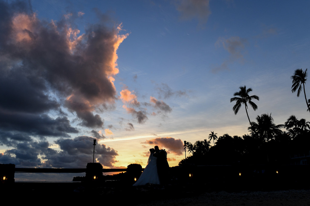 Silhouette of bride and groom kissing in Stunning Fiji sunset over palm trees and Warwick