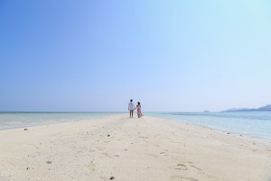 The couple stroll into the horizon of a cloudless blue sky at the reef
