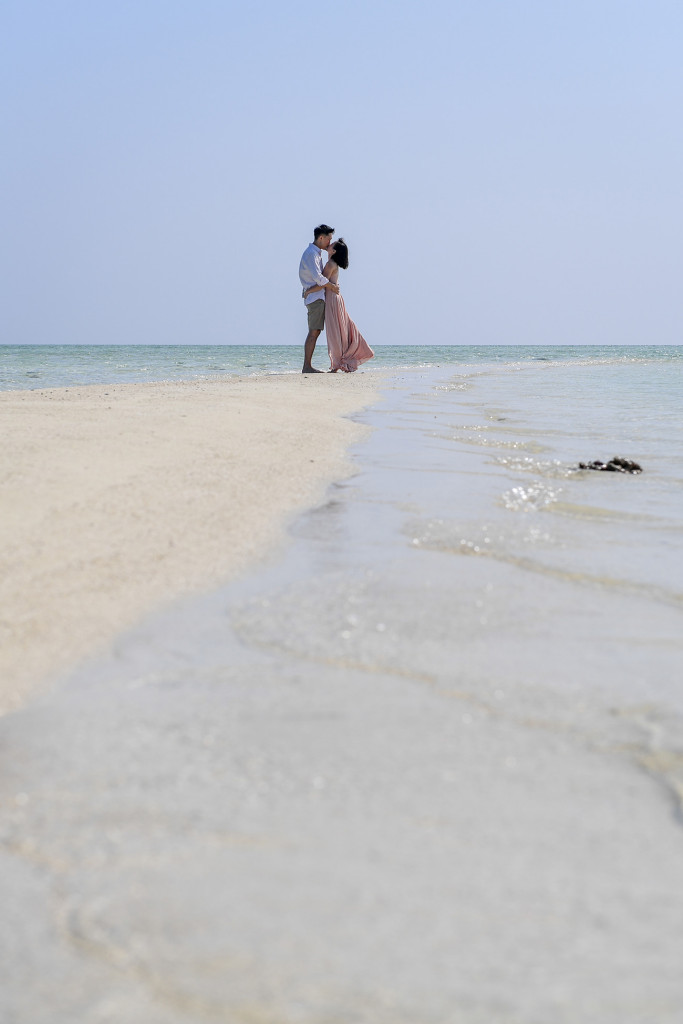 The newly married couple passionately kiss in the horizon at the edge of the reef