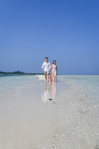 The couple strolls toward the camera with the cloudless deep blue sky behind them