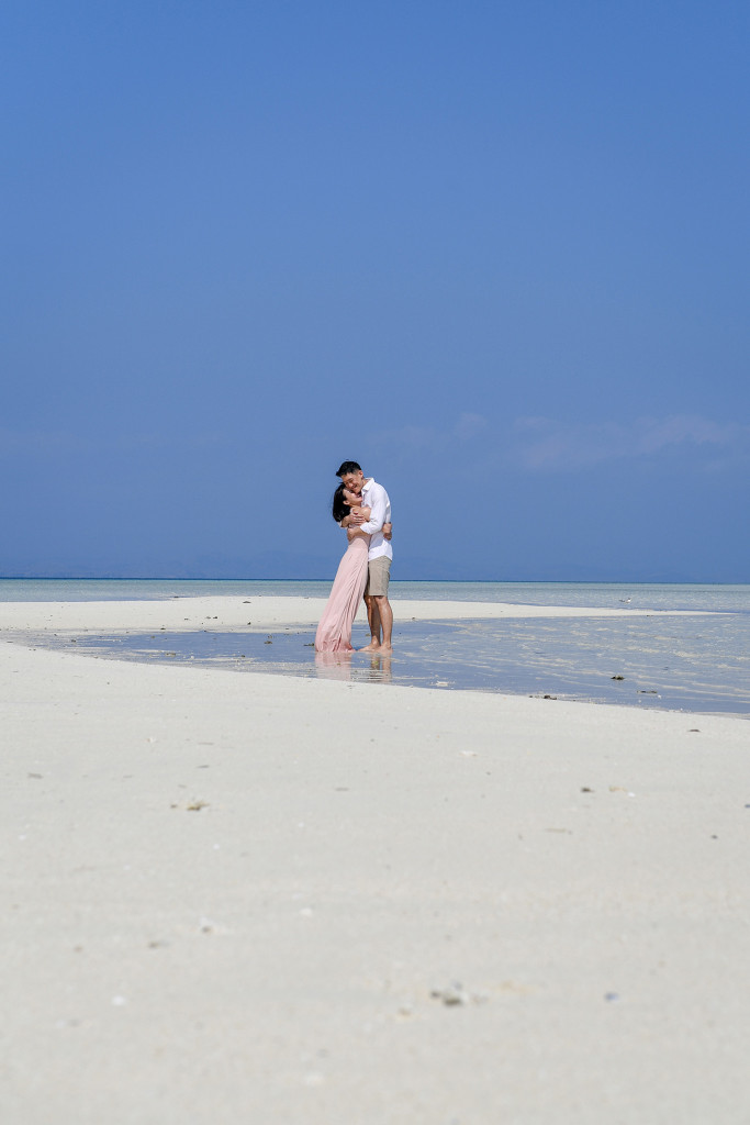 The couple hugs on the shores of the shallow waters of the reef