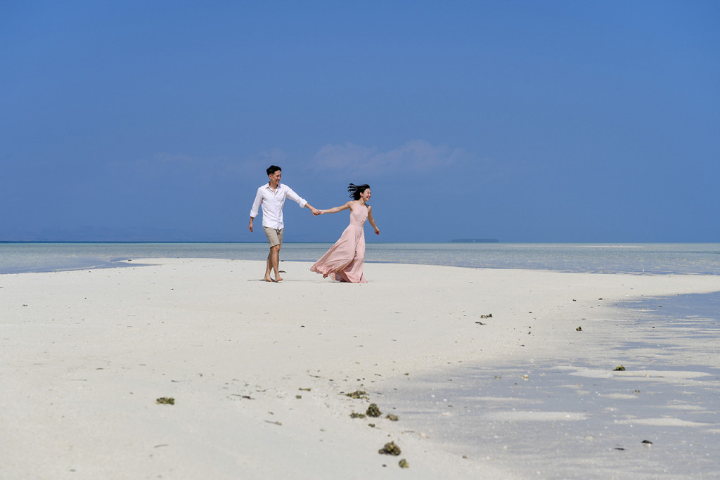 The bride runs towards the sea at Malolo Lai Lai Island with her husband in tow