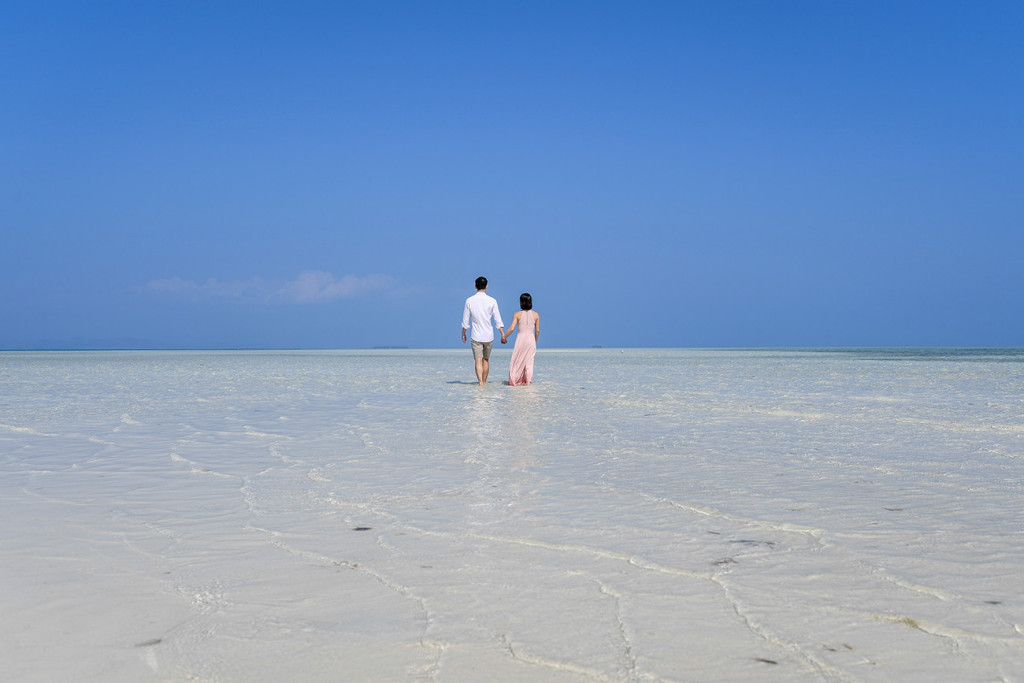 The couple wades in the subsiding waters of Malolo Lai Lai Island at Lomani Island Resort